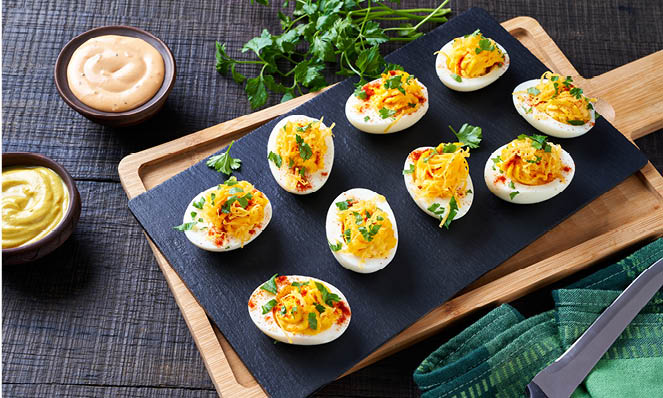 deviled-eggs-stone-tray-wood-serving-board-sauces-green-garnishes